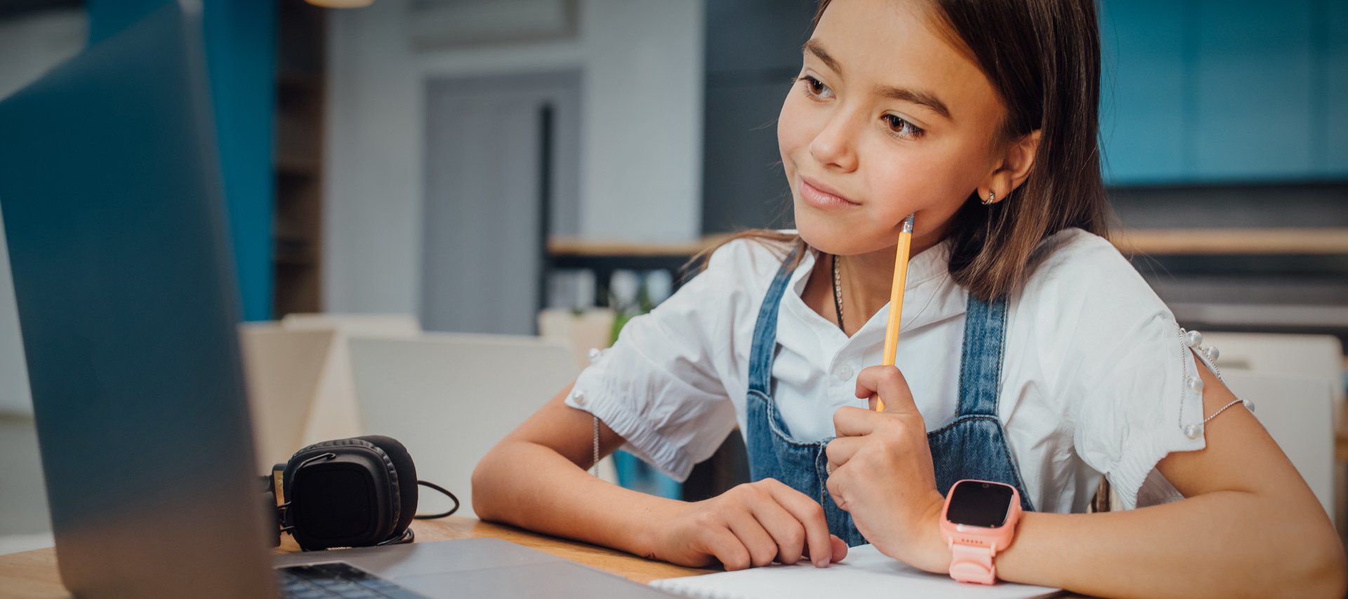 Composição de foto com ilustração. Menina com os braços apoiados na mesa. Na mão esquerda segura um lápis pela ponta, e o lado oposto dele encosta na bochecha. Ela olha para a tela do notebook que está a sua frente.
            Sobre a foto, duas ilustrações: à direita, personagem arara apoiada na mesa, a esquerda o personagem Francisco que está de pé e sorri. Acima dele um balão de fala que diz "Nós aprendemos juntos e de muitas maneiras.”